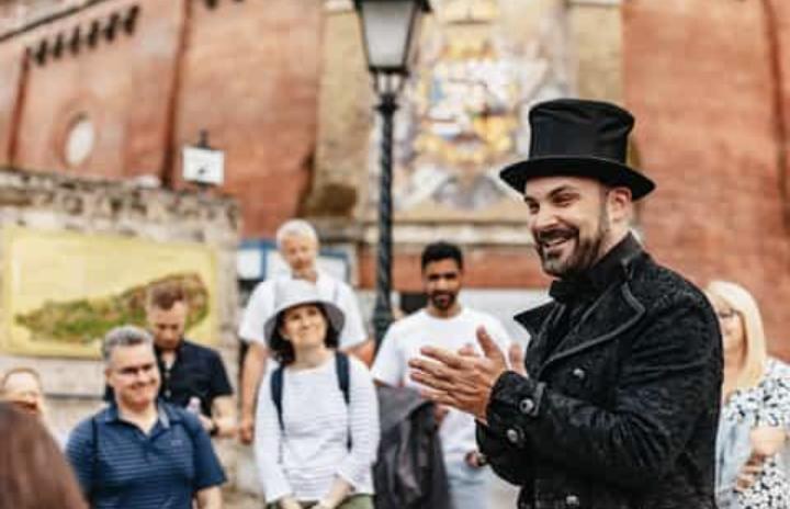 Darsteller mit Zylinder führt eine Gruppe durch eine Schweizer Altstadt